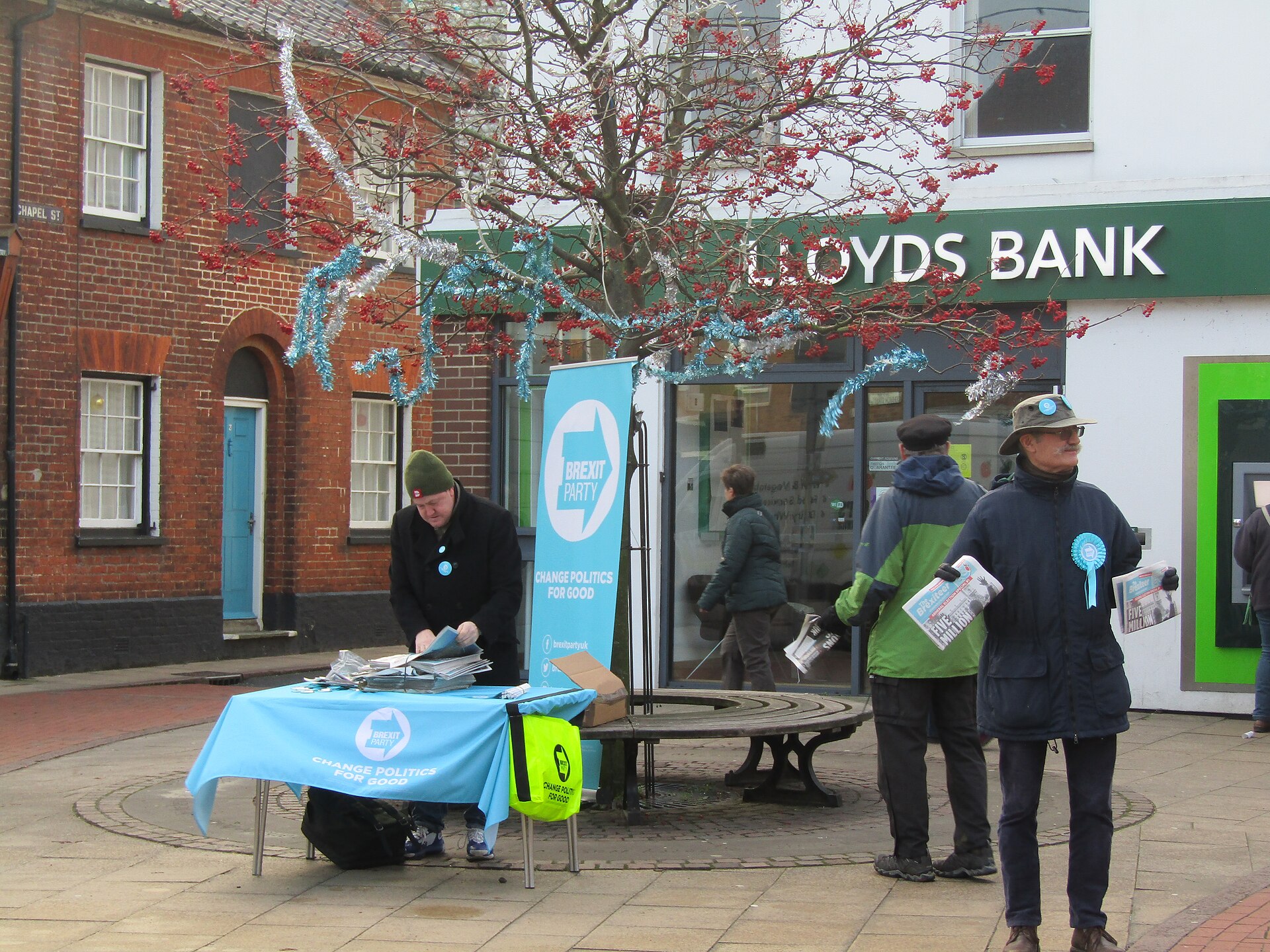 Brexit Party volunteers campaign outside a Lloyds Bank branch, demonstrating political activism at an event.