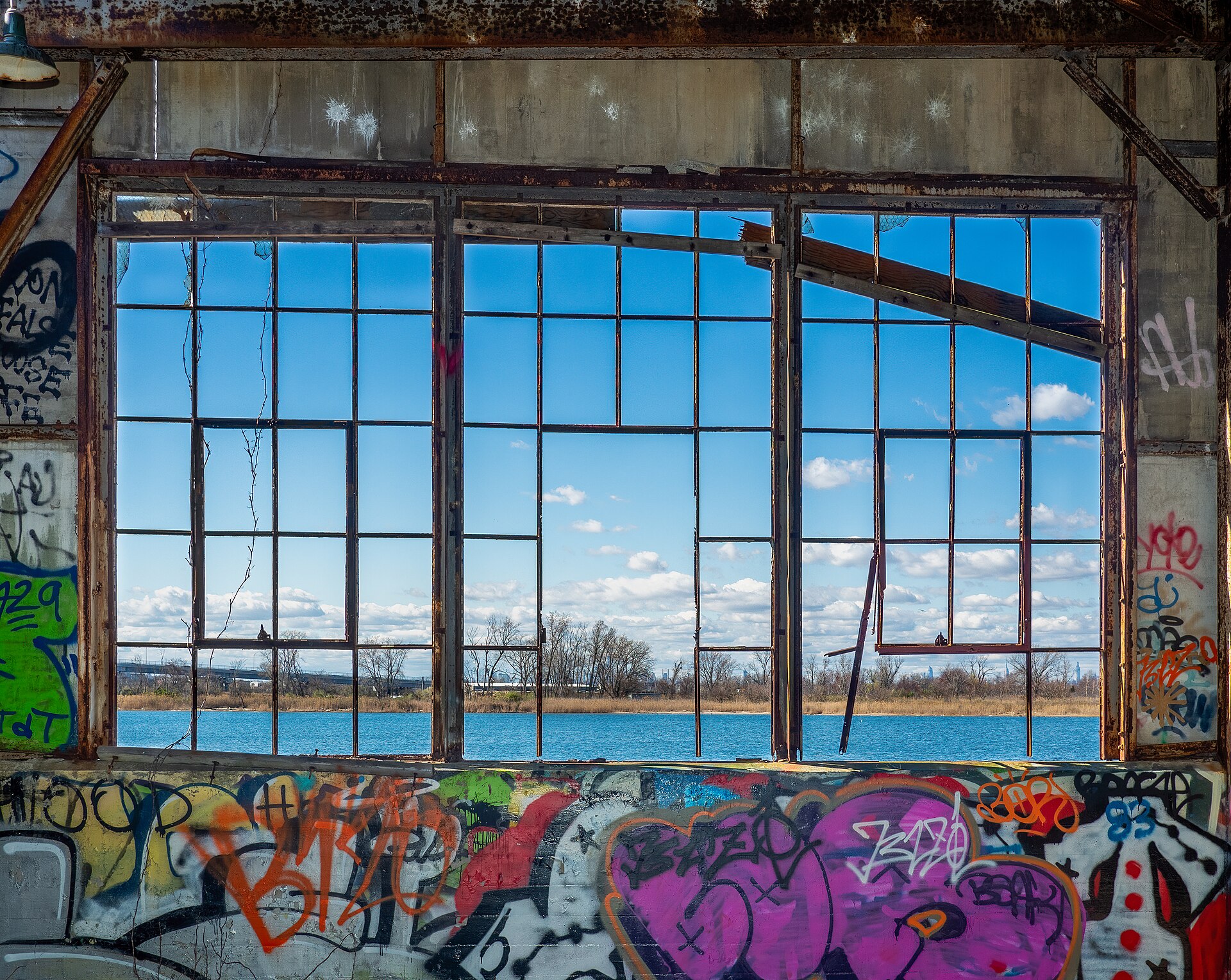 A derelict building window frames a view of water and distant land, illustrating the potential for unique event spaces.