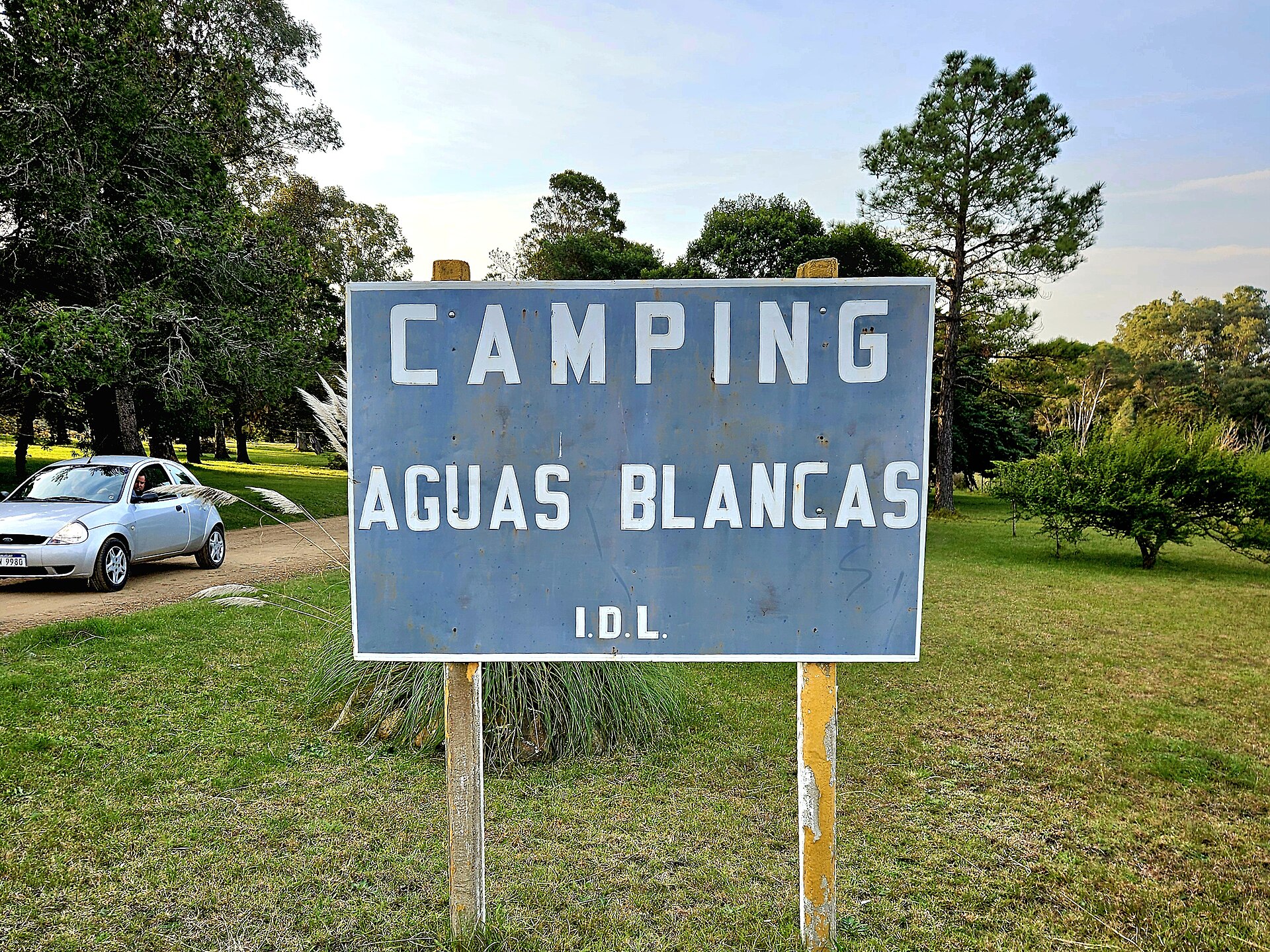 A roadside camping sign for Aguas Blancas is visible near a field, useful information for first time festival attendees.