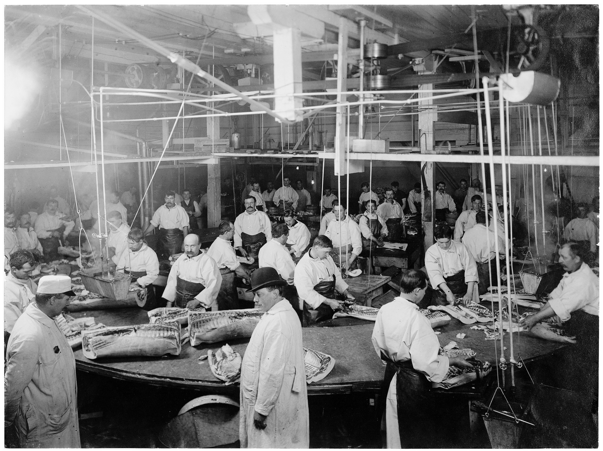 A group of factory workers process fish at a circular table, relating to planning for large events.