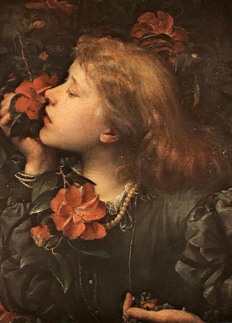 A young person with red hair gently smells a vibrant red camellia flower at an event.